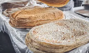 Stos cienkich, okrągłych placków lawaszu na stole, niektóre z nich lekko przypieczone.