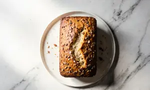 Chleb migdałowy bez glutenu z ziarnami na talerzu na marmurowym tle.