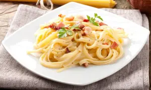 Talerz spaghetti carbonara z boczkiem i natką pietruszki.