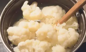 Kalafior gotujący się w garnku, mieszany drewnianą łyżką.