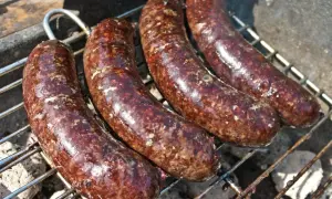 Cztery soczyste kaszanki z grilla pieką się na ruszcie, uwalniając apetyczny aromat.