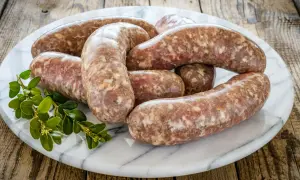 Surowa kiełbasa na marmurowej desce, gotowa do przyrządzenia. Zastanawiasz się, ile czasu parzyć surową kiełbasę?