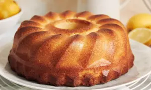 Puszysta babka z wgłębieniem pośrodku, na talerzu, z cytrynami w tle.