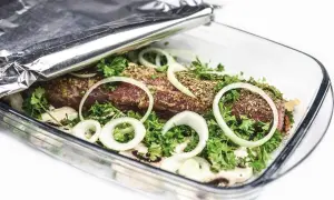 Mięso w naczyniu żaroodpornym pod folią aluminiową, z cebulą i ziołami.