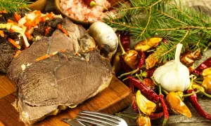 Gotujesz dziczyznę? Na stole pieczone mięso, czosnek, papryczki chili i przyprawy. Idealne składniki, by dowiedzieć się, jak przyrządzić dziczyznę.