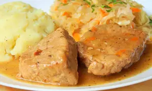 Soczysta szynka wieprzowa w sosie, podana z puree ziemniaczanym i surówką z kiszonej kapusty. Idealny pomysł, jak zrobić szynkę wieprzową na obiad.
