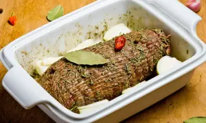 Rolada mięsna w naczyniu żaroodpornym, gotowa do pieczenia. To idealny przepis na szynkę na obiad, z cebulą i ziołami.