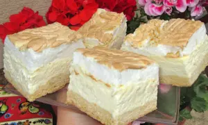 Kawałki sernika z pianką bezową i złotymi okruszkami na tle kwiatów.