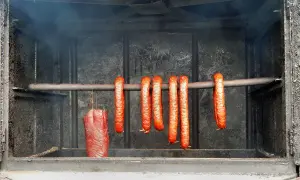 Wędzone kiełbaski i kawałek mięsa wiszące w wędzarni.