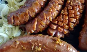 Pyszna kiełbasa grillowa z serem, pokrojona w plastry, podana na cebuli. Idealny przepis na letnie grillowanie!