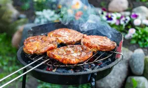 Soczysty karczek na grillu, idealny przykład, jak zamarynować karczek na grilla. Dym unosi się nad grillowanymi mięsami.