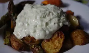 Gęsty sos tzatziki na pieczonych ziemniakach i warzywach.