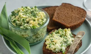 Jajeczna pasta z czosnkiem niedźwiedzim w słoiku i na kromce chleba.
