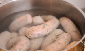 Biała kiełbasa gotuje się w garnku. Kluczowa jest odpowiednia temperatura parzenia, by była soczysta.