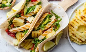 Tacos z grillowanym kurczakiem, ananasem i warzywami, podane z cytryną.