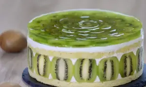 Tort z galaretką kiwi i plasterkami kiwi na bokach.