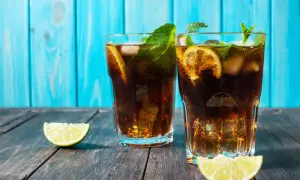 Dwa drinki z rumem, lodem, cytryną i miętą na drewnianym stole.