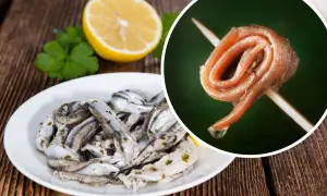 Anchois na talerzu i pojedynczy filet na wykałaczce, obok cytryna i natka.