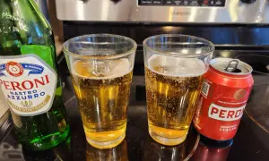 Butelka i puszka Peroni Nastro Azzurro obok dwóch szklanek piwa.