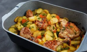 Szybki obiad z piekarnika: pieczony kurczak z ziemniakami, cukinią i marchewką, posypany świeżym koperkiem.