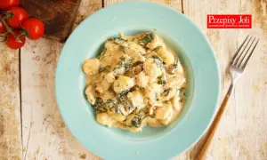 Gnocchi z kurczakiem i szpinakiem w kremowym sosie na niebieskim talerzu.
