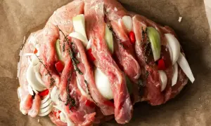 Surowa szynka z cebulą, papryczką chili i ziołami, gotowa do pieczenia na obiad.