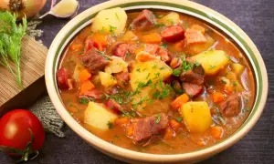 Gęsty gulasz z ziemniakami, mięsem i kiełbasą, posypany natką. Idealny obiad na dwa dni, sycący i aromatyczny.