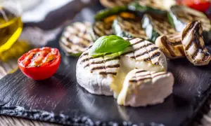Grillowany ser Camembert z pomidorkiem i warzywami na czarnym kamieniu.
