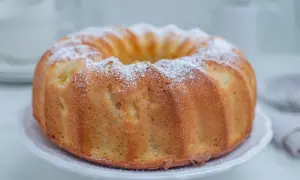 Puszysta babka cytrynowa posypana cukrem pudrem na białej paterze.