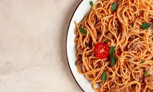 Talerz spaghetti bolognese z pomidorkiem i bazylią. Idealne dodatki do spaghetti, które zachwycą każdego smakosza.