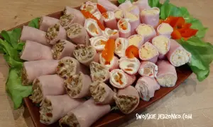 Roladki z szynki z różnymi nadzieniami, ułożone na talerzu z sałatą i papryką.