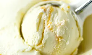 Łyżka do lodów nakłada kremowe lody waniliowe z pomarańczowymi smugami.