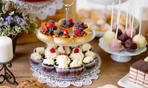 Stół z babeczkami, tartaletkami z owocami, cake pops i ciastem.