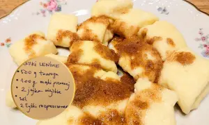 Kluski leniwe polane cynamonem na talerzu z przepisem.