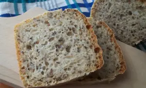 Kromki domowego chleba z ziarnami na desce do krojenia.