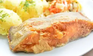 Smażony filet z ryby z ziemniakami i surówką na talerzu.