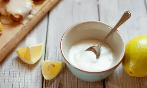 Miska z lukrem, cytryny i łyżeczka na drewnianym tle.