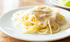 Kremowy sos serowy na makaronie spaghetti na białym talerzu.