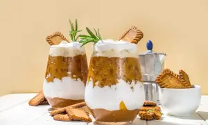 Dwa szklanki kawy z bitą śmietaną, ciasteczkami Biscoff i rozmarynem.