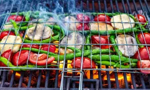 Warzywa na grillu: pomidory, papryczki i plastry bakłażana na ruszcie nad żarem.