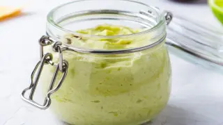 Kremowa pasta z awokado i serka w słoiku, z otwartą pokrywką.