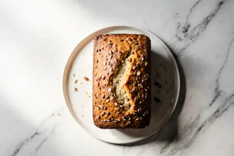 Chleb migdałowy bez glutenu z ziarnami na talerzu na marmurowym tle.
