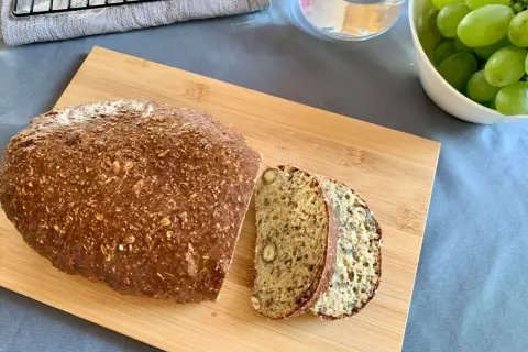 Chleb z twarogu z ziarnami i orzechami, pokrojony na desce.