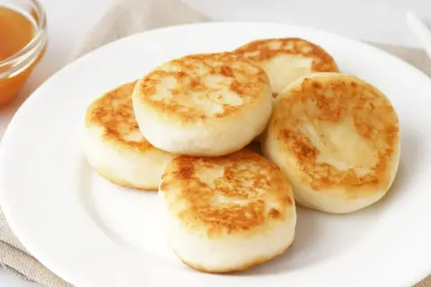 Złociste placuszki z twarogu na talerzu. Idealne pytanie: co zrobić z twarogu na kolację?