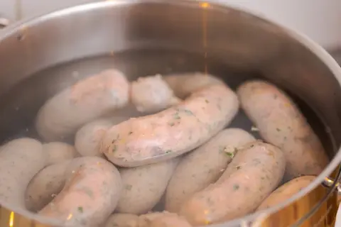 Biała kiełbasa gotuje się w garnku. Kluczowa jest odpowiednia temperatura parzenia, by była soczysta.