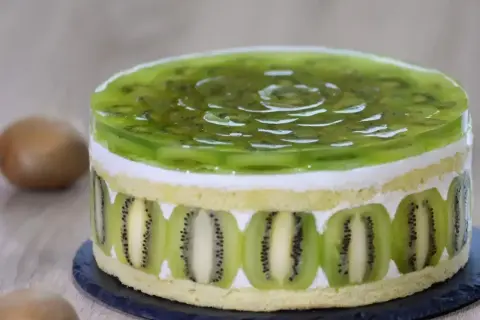 Tort z galaretką kiwi i plasterkami kiwi na bokach.