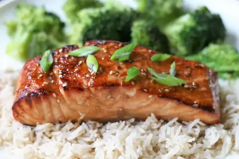 Łosoś w sosie teriyaki z ryżem i brokułami, posypany sezamem i szczypiorkiem.