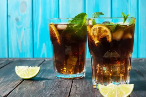Dwa drinki z rumem, lodem, cytryną i miętą na drewnianym stole.