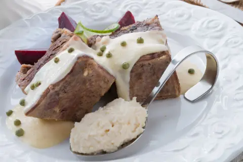 Kawałki mięsa w sosie chrzanowym z zielonym pieprzem, burakami i łyżką tartego chrzanu.