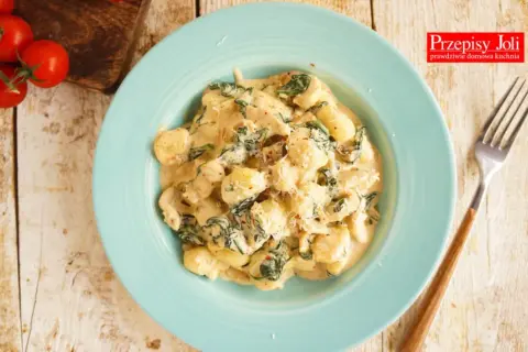 Gnocchi z kurczakiem i szpinakiem w kremowym sosie na niebieskim talerzu.
